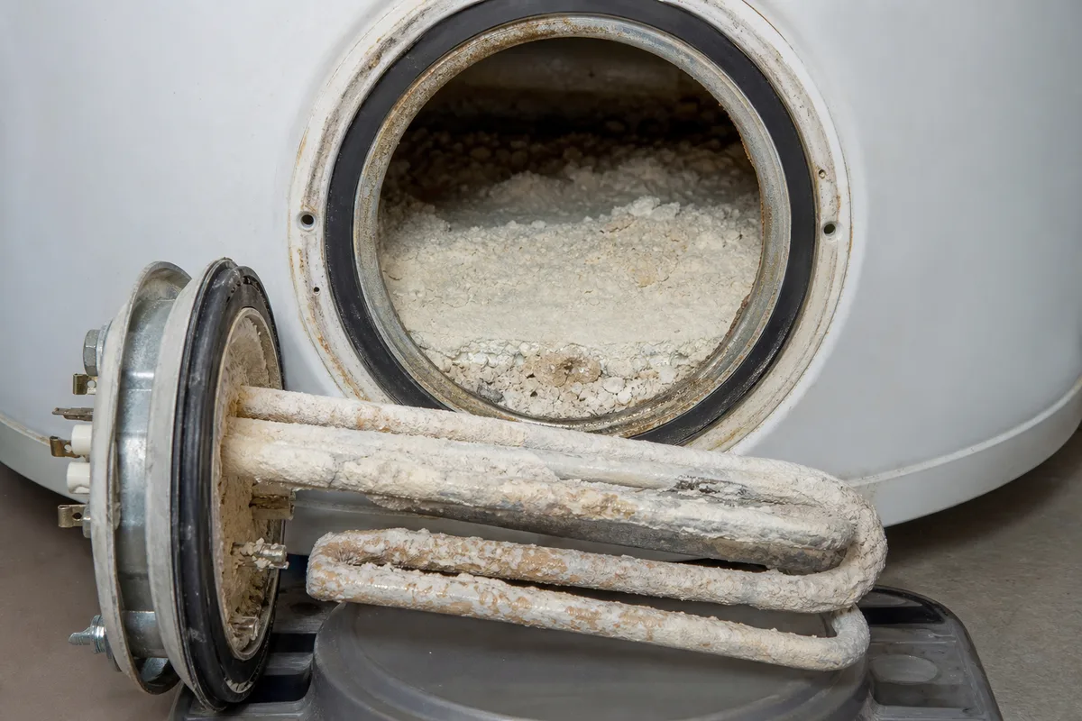 Cuve ouverte d&rsquo;un chauffe-eau électrique montrant la résistance recouverte d&rsquo;une épaisse couche de tartre calcaire