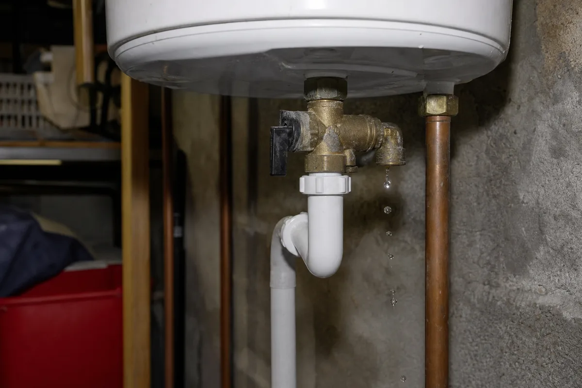 Groupe de sécurité de chauffe-eau en laiton avec siphon d&rsquo;évacuation, gouttes d&rsquo;eau visibles sous la soupape