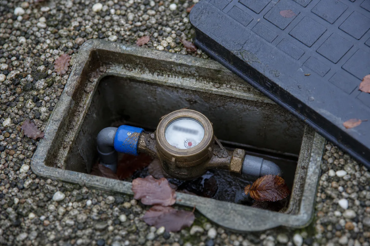 Compteur d’eau domestique dans un regard ouvert, index chiffré visible en gros plan